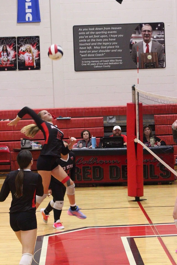 calhoun team memeber is in mid air preparing to hit the ball over the net
