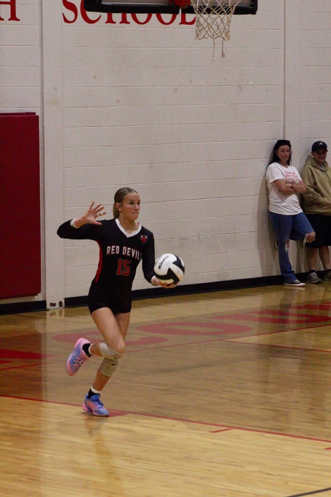 Number 15 serving the ball over the net