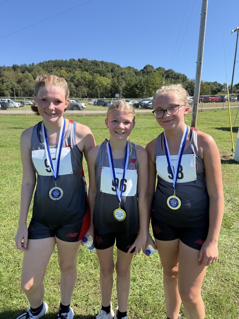 3 Middle school girls pose with award medals around neck