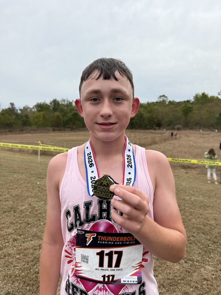 Middle School runner stands with medal in hand