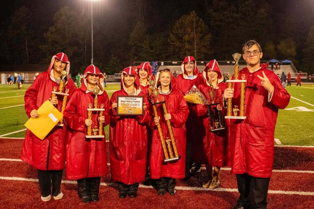 Band members stand in raincoats with awards from the festival. 