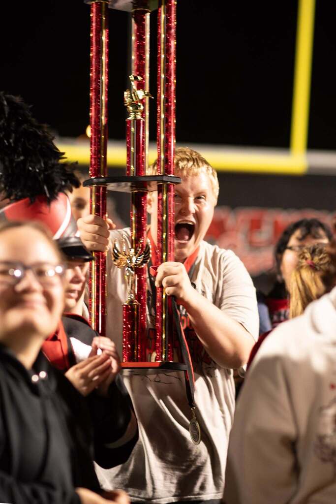 Student holds teh grand champion trophy in his hands while yelling in joy.