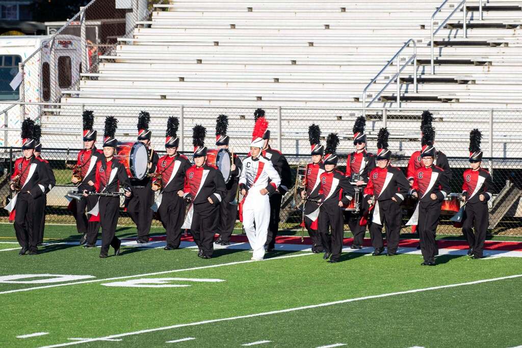 Calhoun Band in Red and black uniforms march across field led by Drum major in white and red