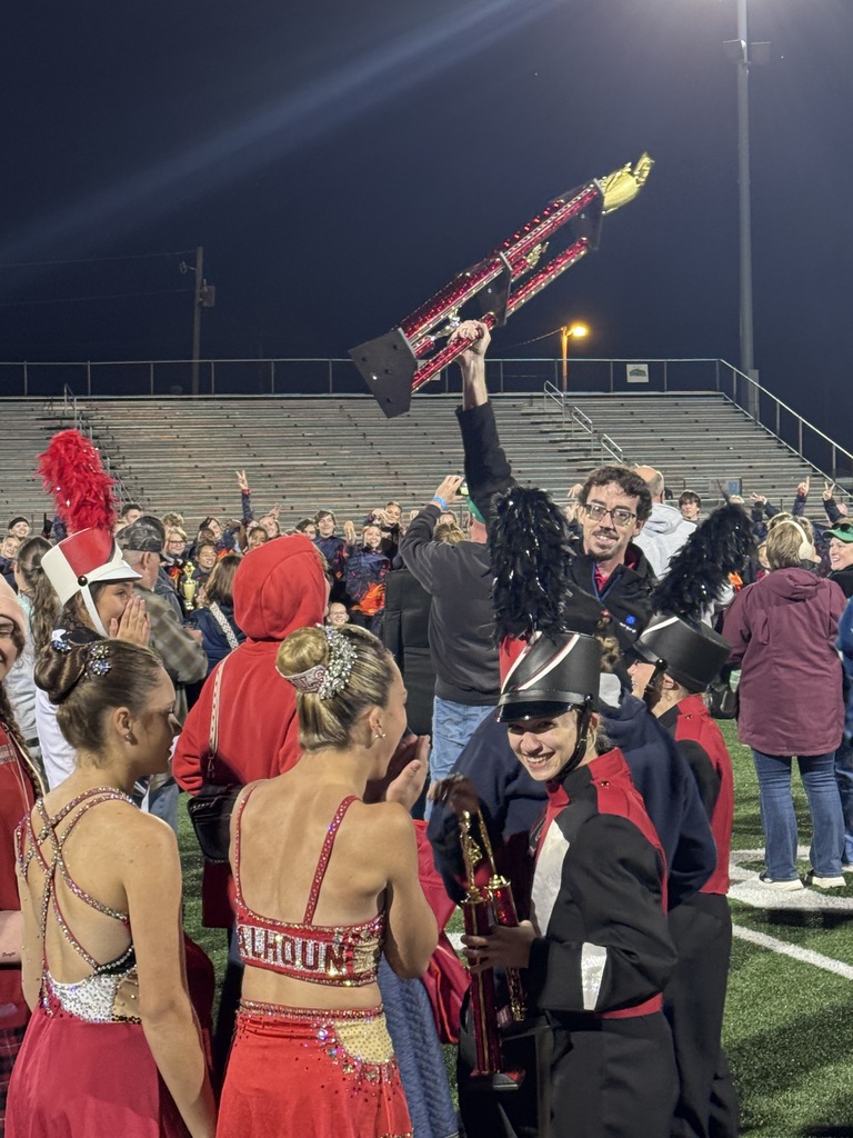 Mr. McHenry, with a big smile on his face, holds tropy in air with band members surrounding him