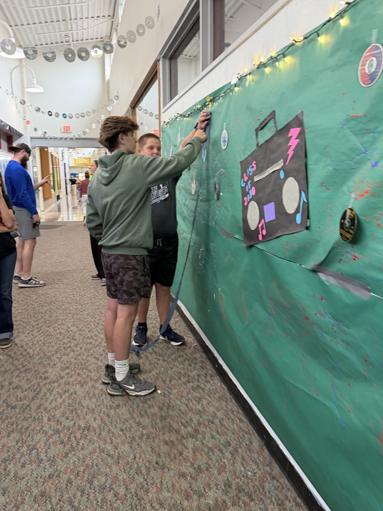 Freshman decorating their hallway with lights and CD or DVD garland draped across the lockers.
