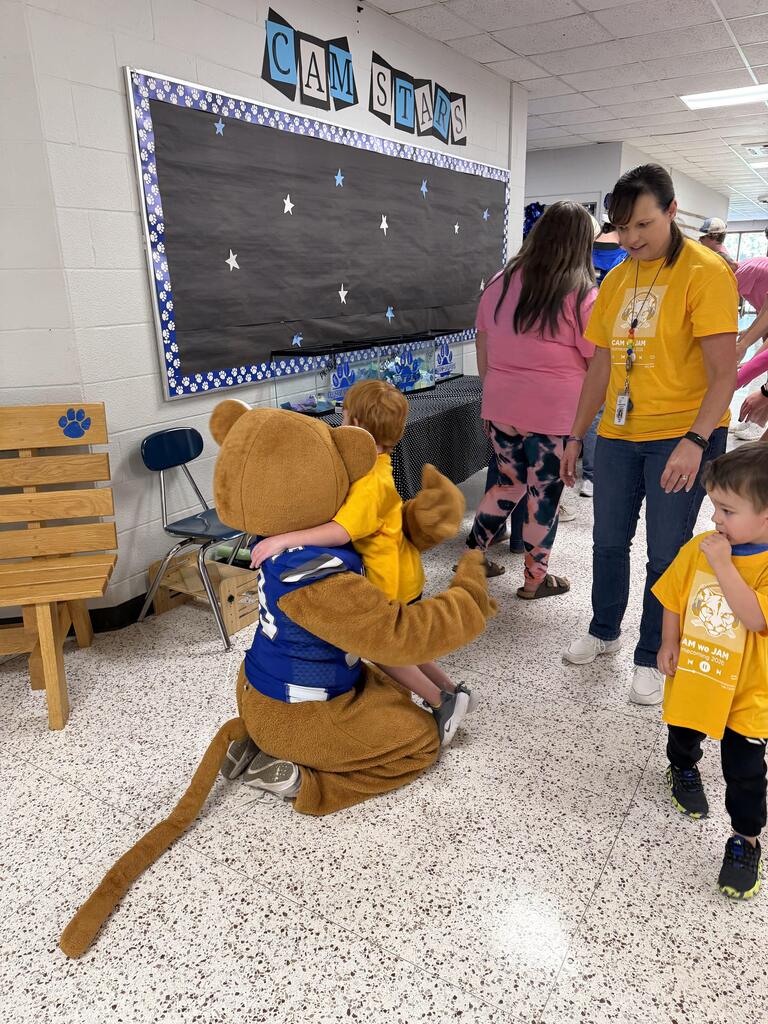 The Cougar mascot getting a hug from an elementary student in the hallway