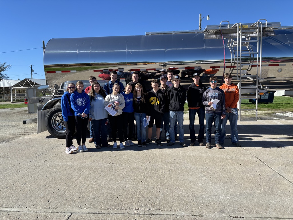 CAM students pose outdoors in front of a shiny silver tanker trailer.