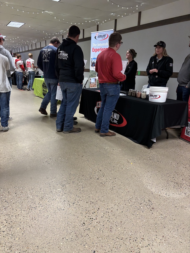Students speak with AGRILAND FS representatives at a career fair booth displaying agricultural samples and internship information.