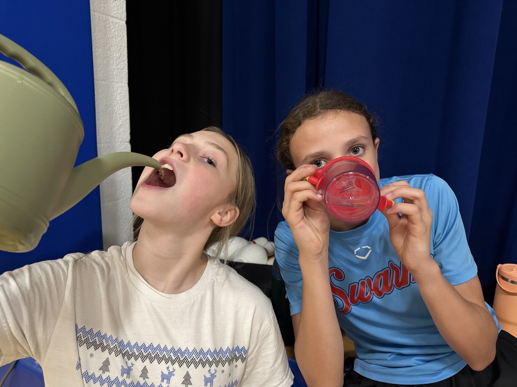 two cam volleyball players. one drinking out of a water jug and another out of a sippy cup