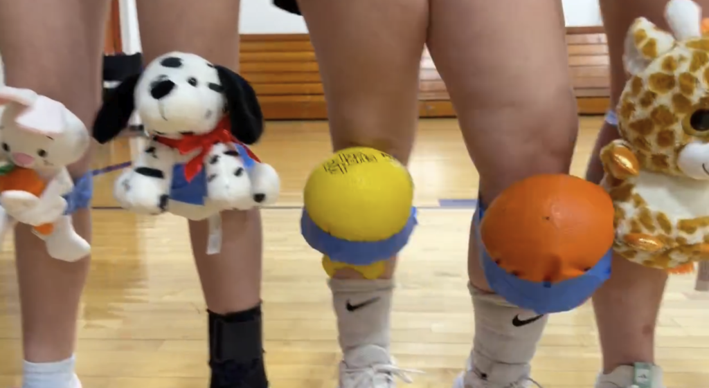 two volleyball players with improv kneepads. one with stuffed animals, and another with dodgeball balls taped with blue electric tape