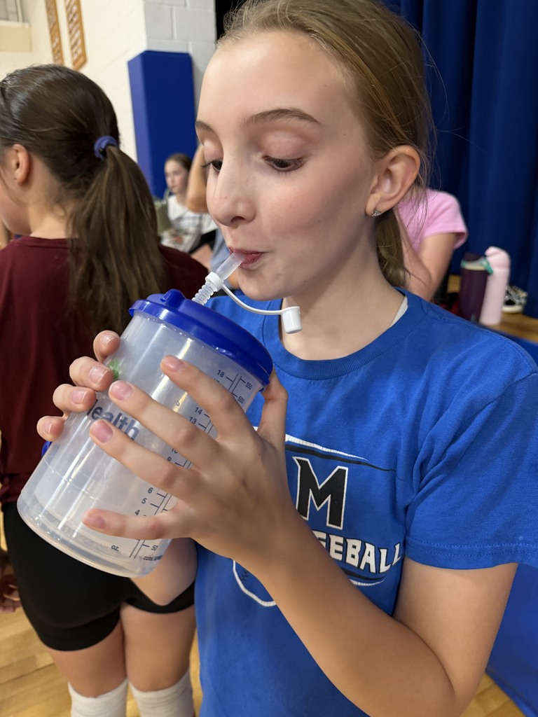 One volleyball player drinking out of a medicine drink cup