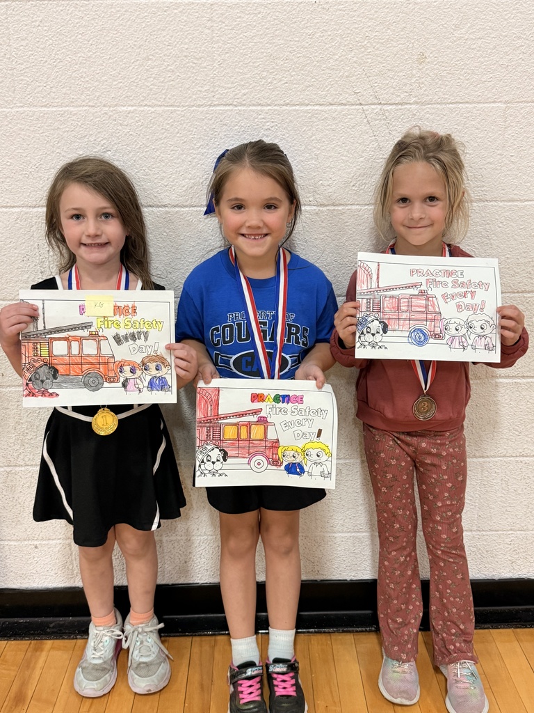 Three CAM students wearing award medals hold their colored fire truck pictures with the message “Practice Fire Safety Every Day.”