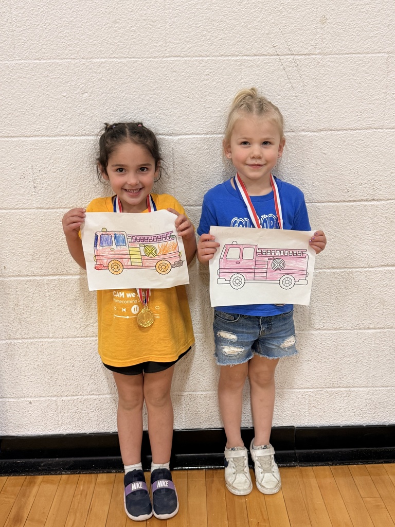 Two CAM students wearing medals display their colorful fire truck coloring pages.