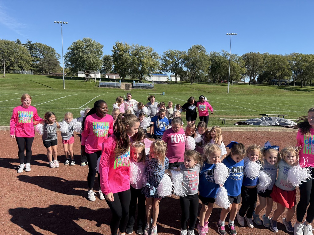 Youth cheerleaders in 4 rows close together practicing a cheer on the track