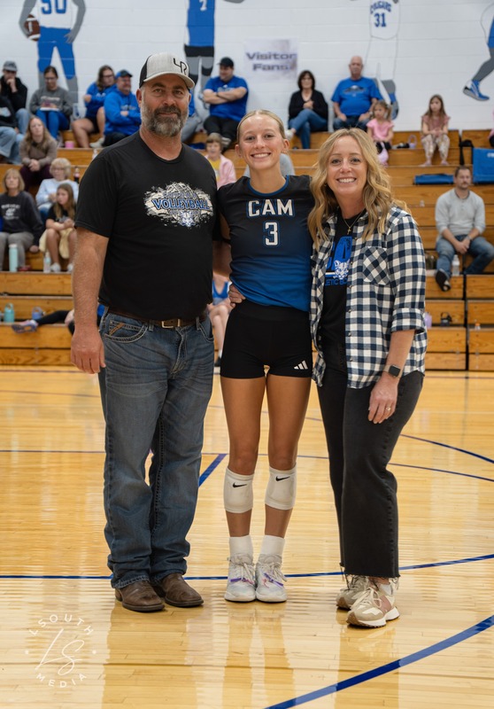 CAM volleyball senior poses with two family members on the gym court.