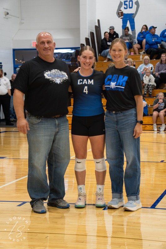 CAM volleyball senior poses with two family members on the gym court.