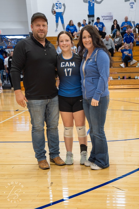 CAM volleyball senior poses with two family members on the gym court.
