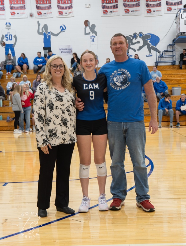 CAM volleyball senior poses with two family members on the gym court.