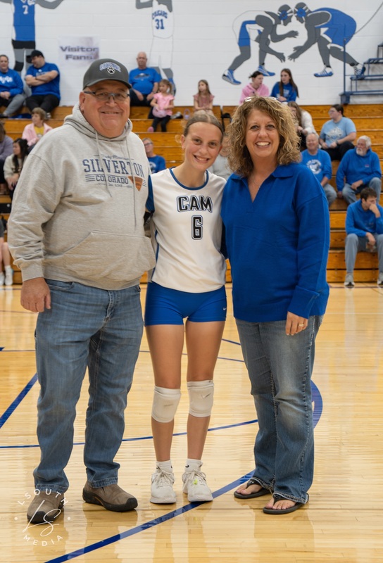 CAM volleyball senior poses with two family members on the gym court.