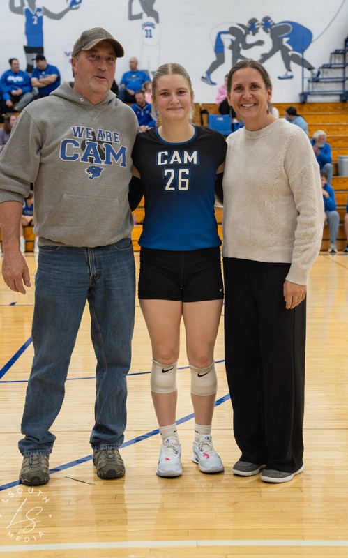 CAM volleyball senior poses with two family members on the gym court.