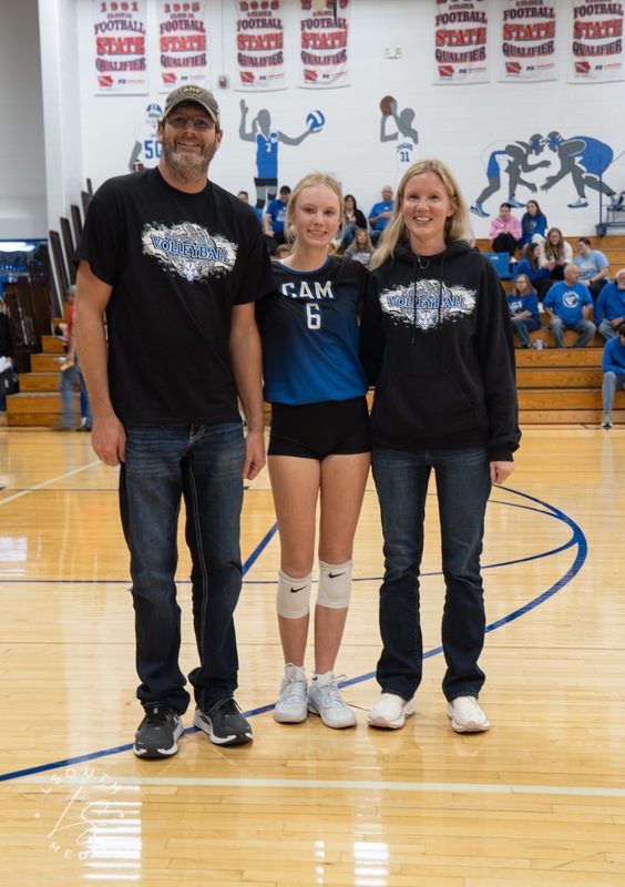 CAM volleyball senior poses with two family members on the gym court.