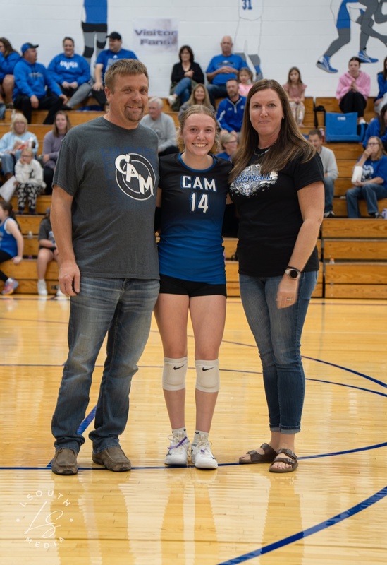 CAM volleyball senior poses with two family members on the gym court.