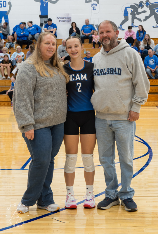 CAM volleyball senior poses with two family members on the gym court.