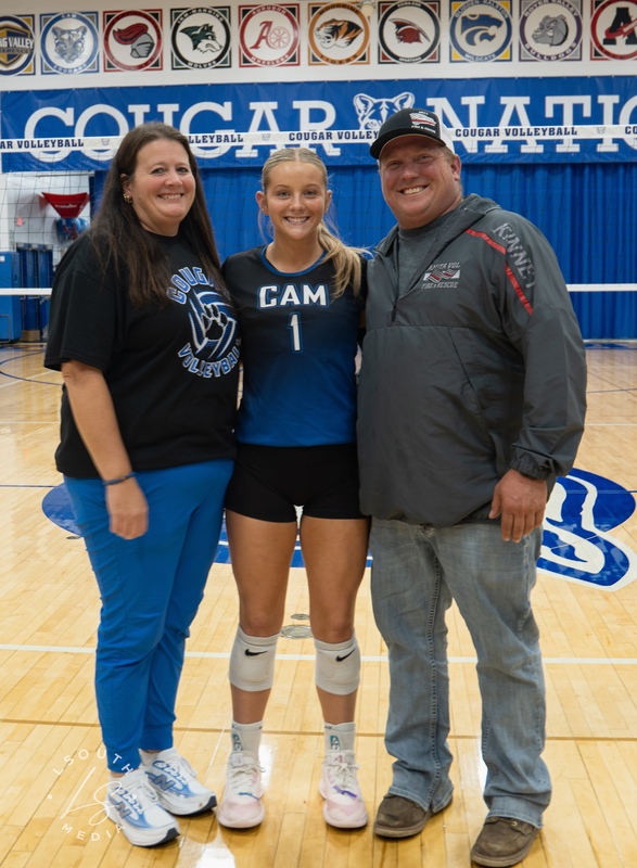 CAM volleyball senior poses with two family members on the gym court.