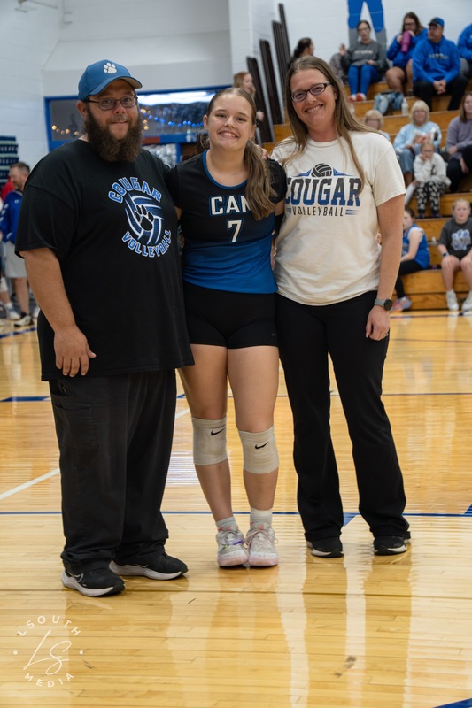 CAM volleyball senior poses with two family members on the gym court.