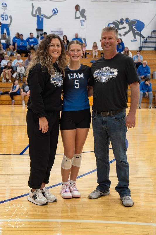 CAM volleyball senior poses with two family members on the gym court.