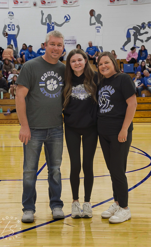 CAM volleyball senior poses with two family members on the gym court.