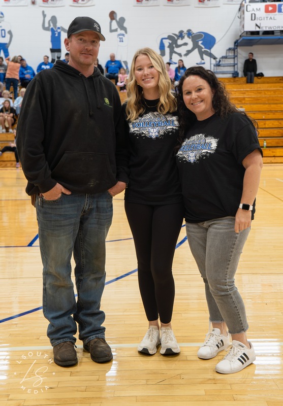CAM volleyball senior poses with two family members on the gym court.