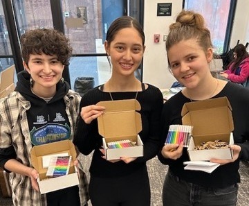 Students holding pens and gifts