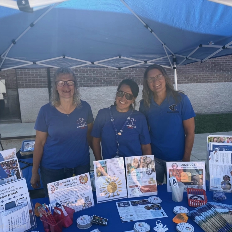 Three Cambridge-Isanti Schools staff welcome families at the Jubilee Days Kids Day information booth.
