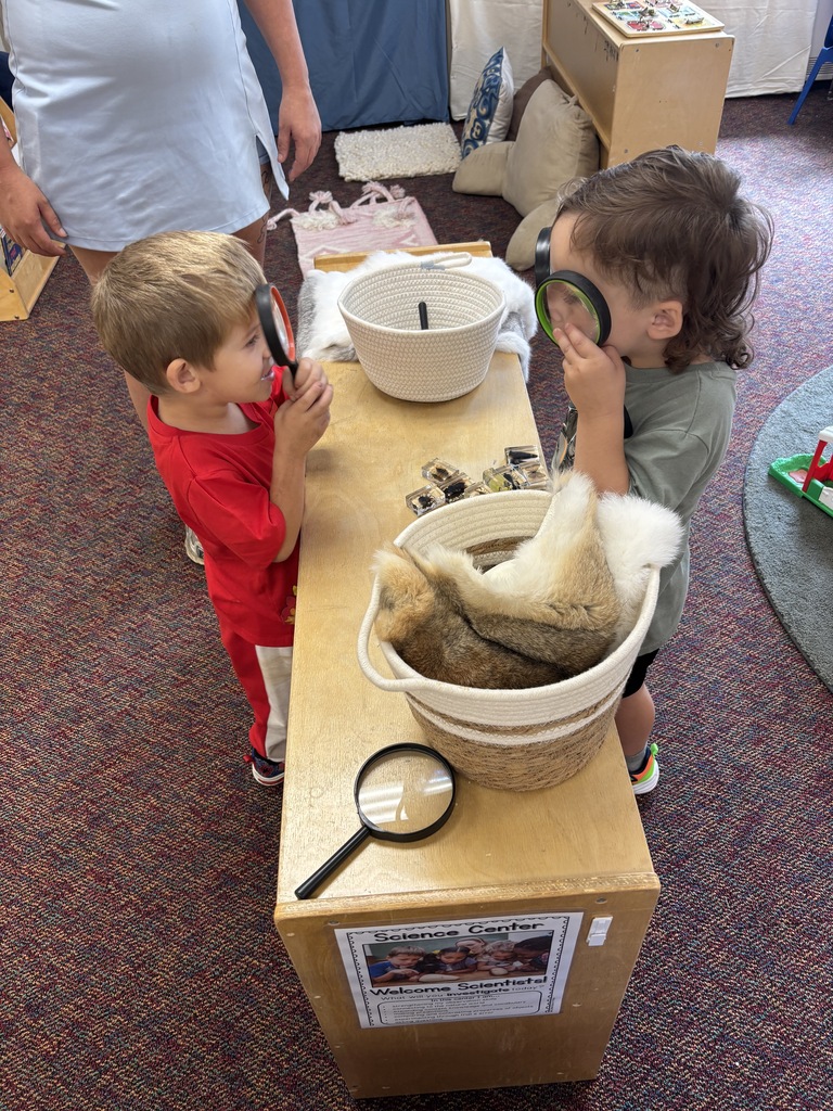 Two young boys looking at each other through magnifying glasses.