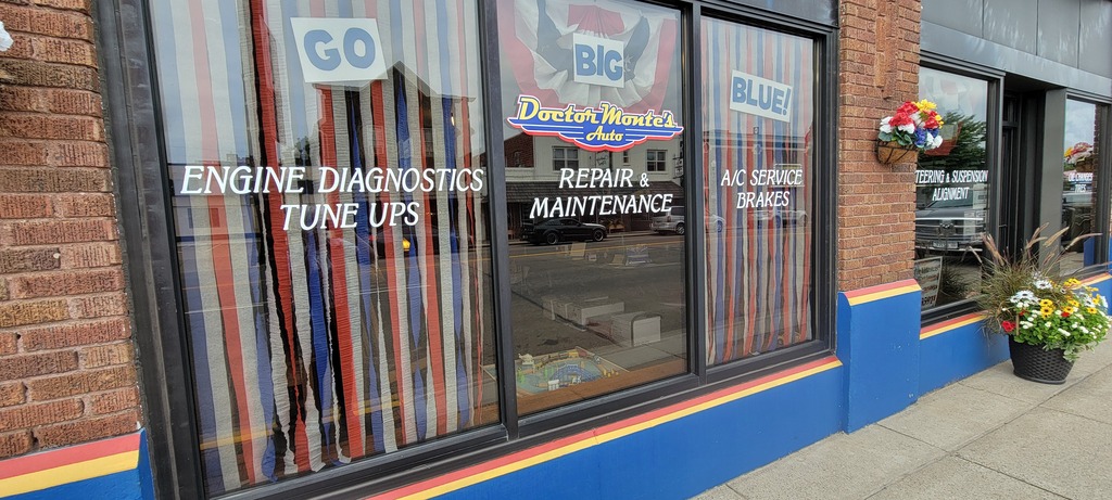 Window front of Doctor Monte's Repair and Maintenance shop. They are displaying their Homecoming pride.