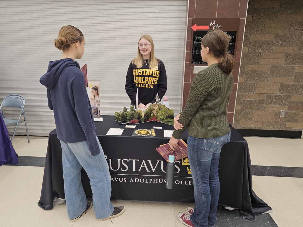 Students speak with a representative at an information table during a college and career fair.