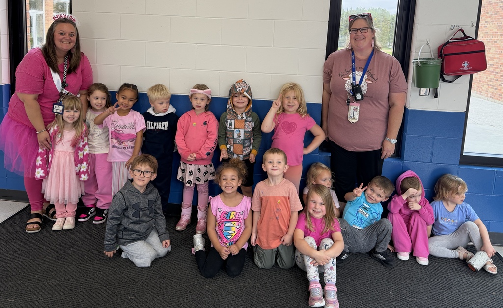 Group photo of preschoolers and 2 teachers smiling  and dressed in pink during "Pink Out Day" for homecoming. 