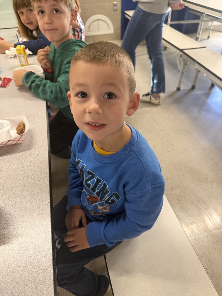 young student sitting with friends at a lunch table finishing up his meal.