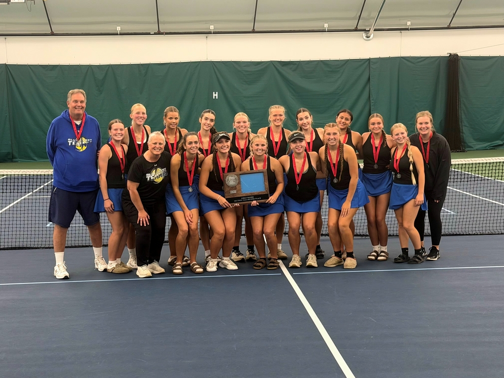 CIHS girls tennis team and coaches pose indoors on a court while smiling and holding a trophy plaque and medals.