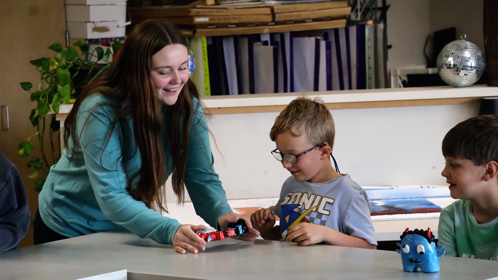 High School Student Delivering Sculpture to Second Grader