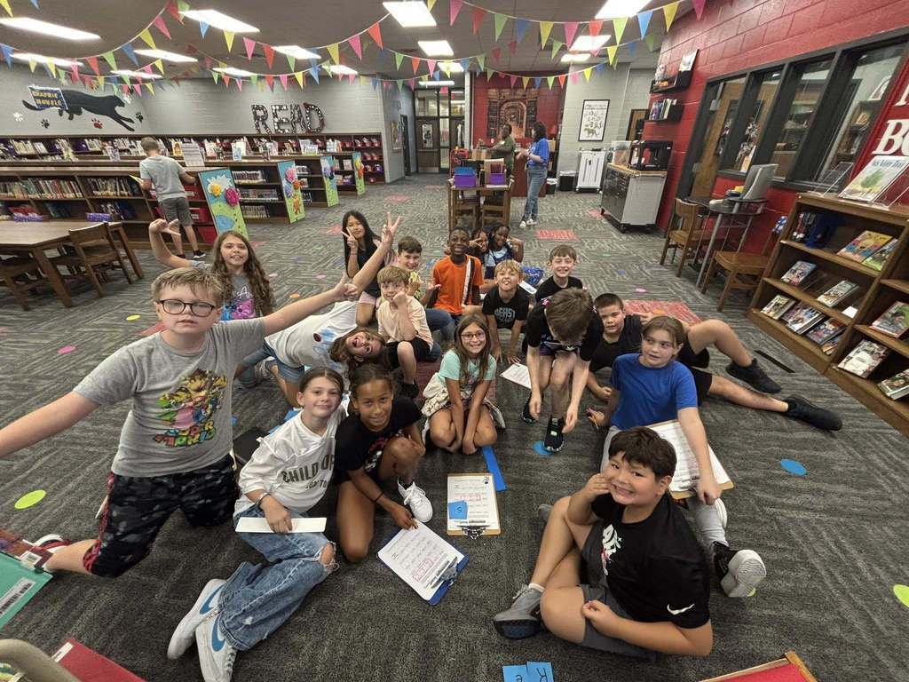 Students smiling at camera while sitting in the library.