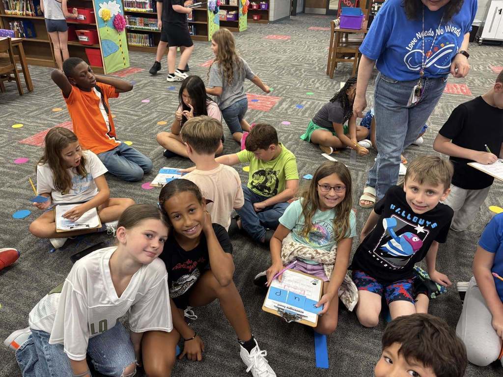 Students smiling at camera while sitting in the library.
