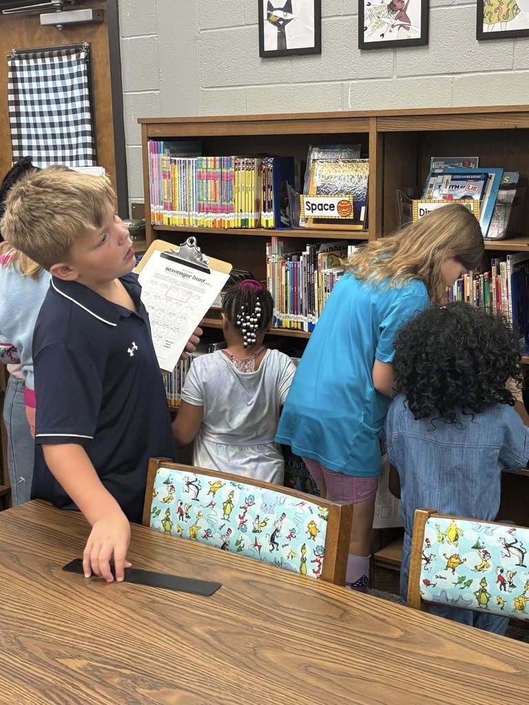 Students working on scavenger hunt in the library, analyzing the bookshelves.