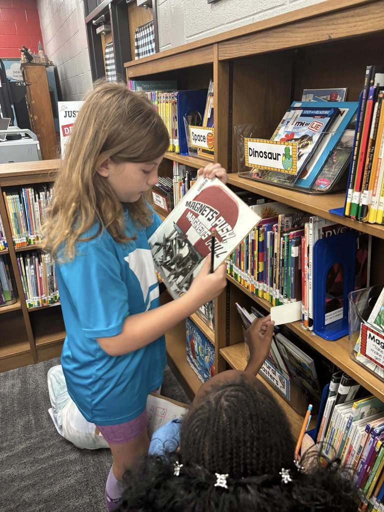 Students working on scavenger hunt in the library, analyzing the bookshelves.