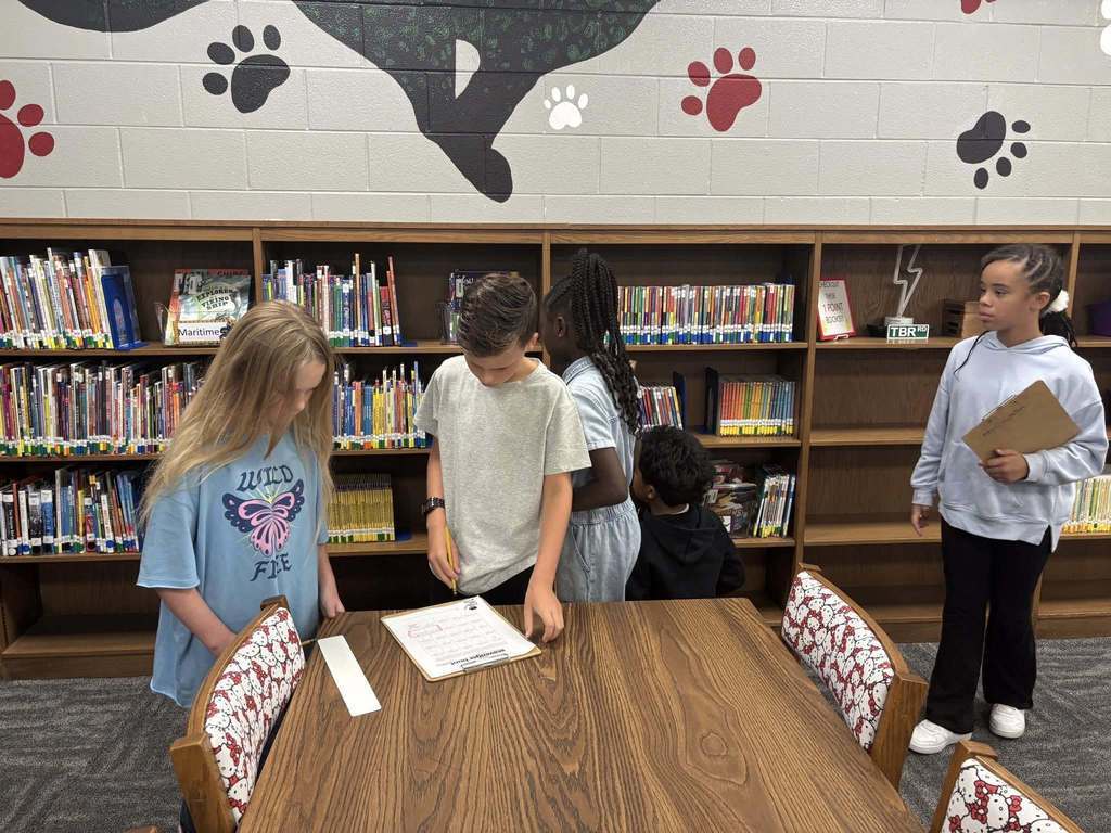 Students working on scavenger hunt in the library, analyzing the bookshelves.