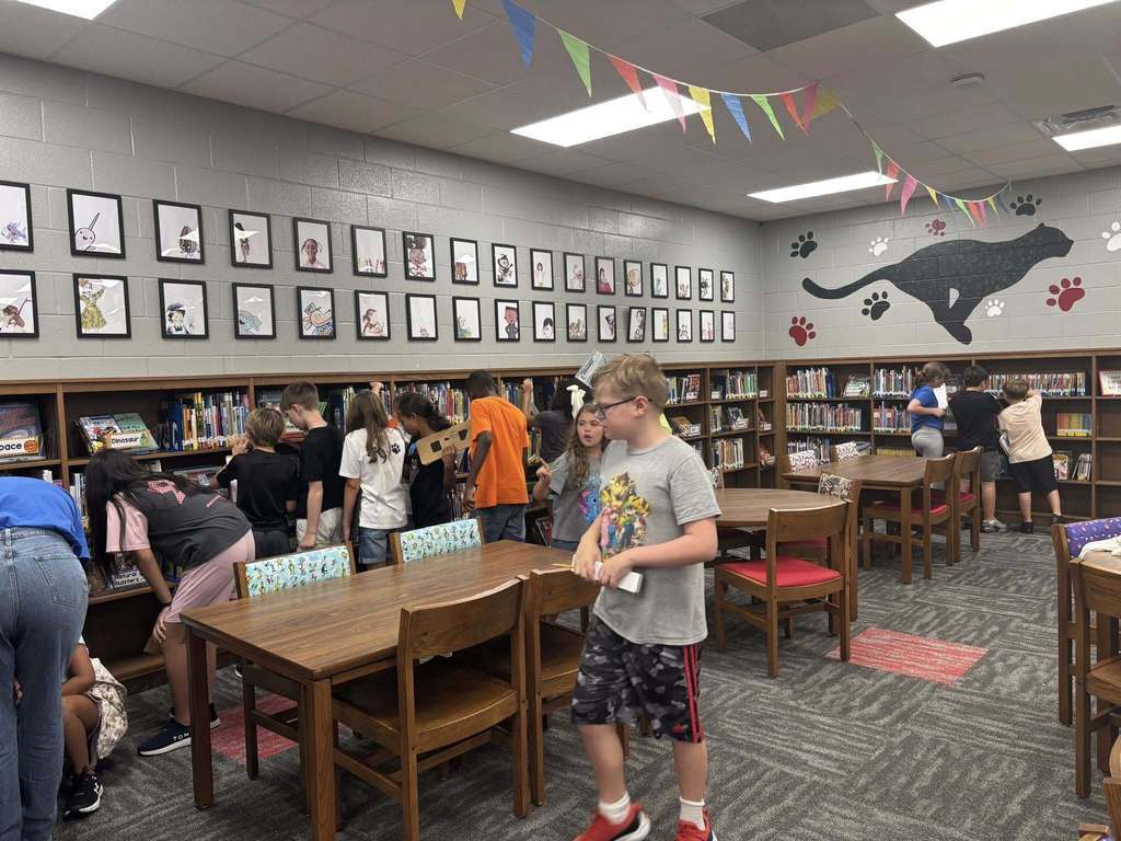 Students working on scavenger hunt in the library, analyzing the bookshelves.