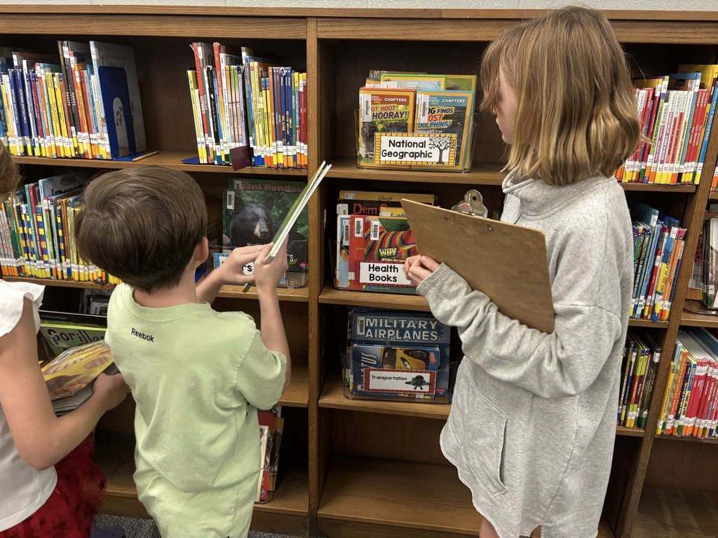 Students working on scavenger hunt in the library, analyzing the bookshelves.