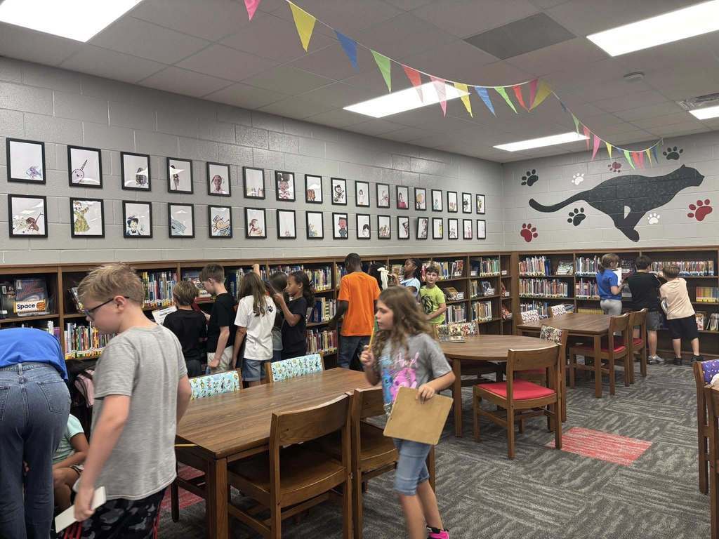 Students working on scavenger hunt in the library, analyzing the bookshelves.