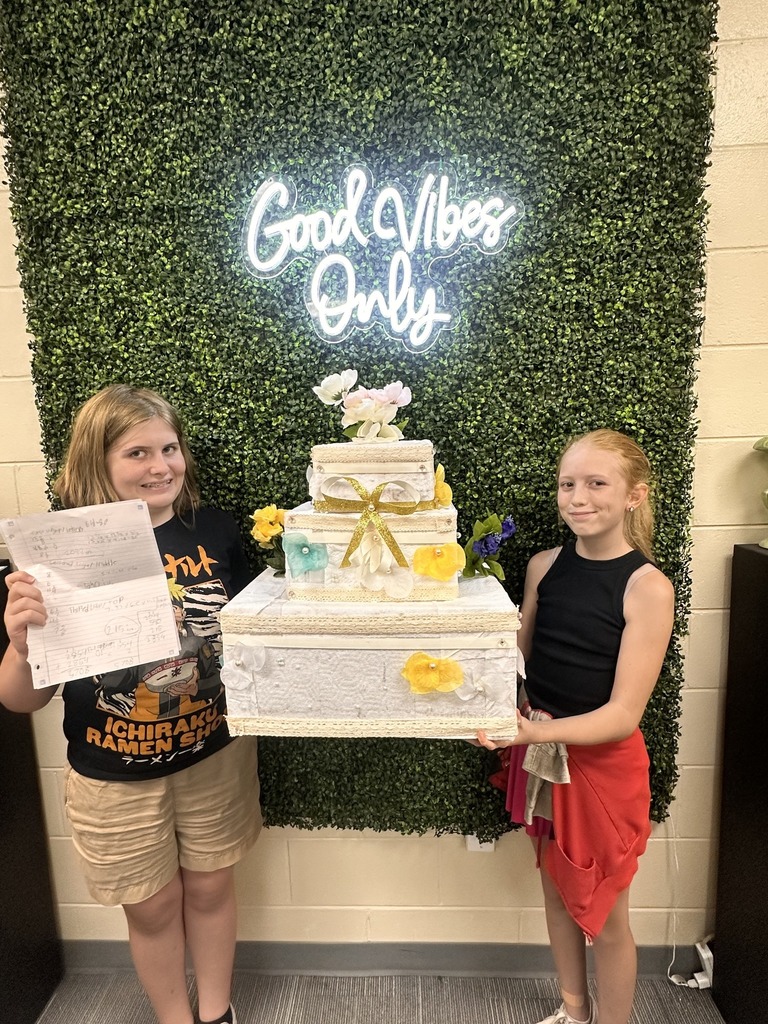 Students standing by the wedding cakes they built